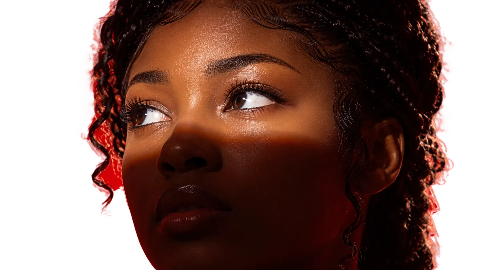 Close-up portrait of a woman looking up, lit by warm orange light